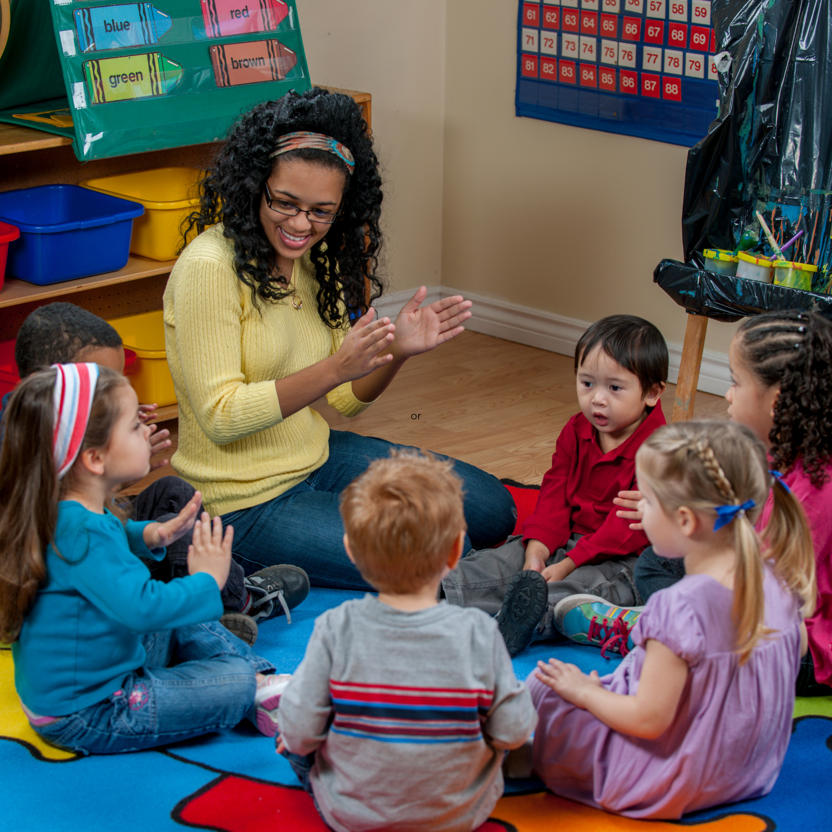 A group of children sit in a circle with their teacher