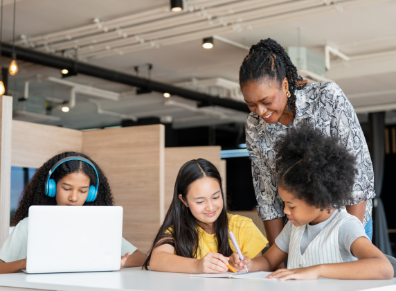 A Black afterschool leader talking with three diverse female students