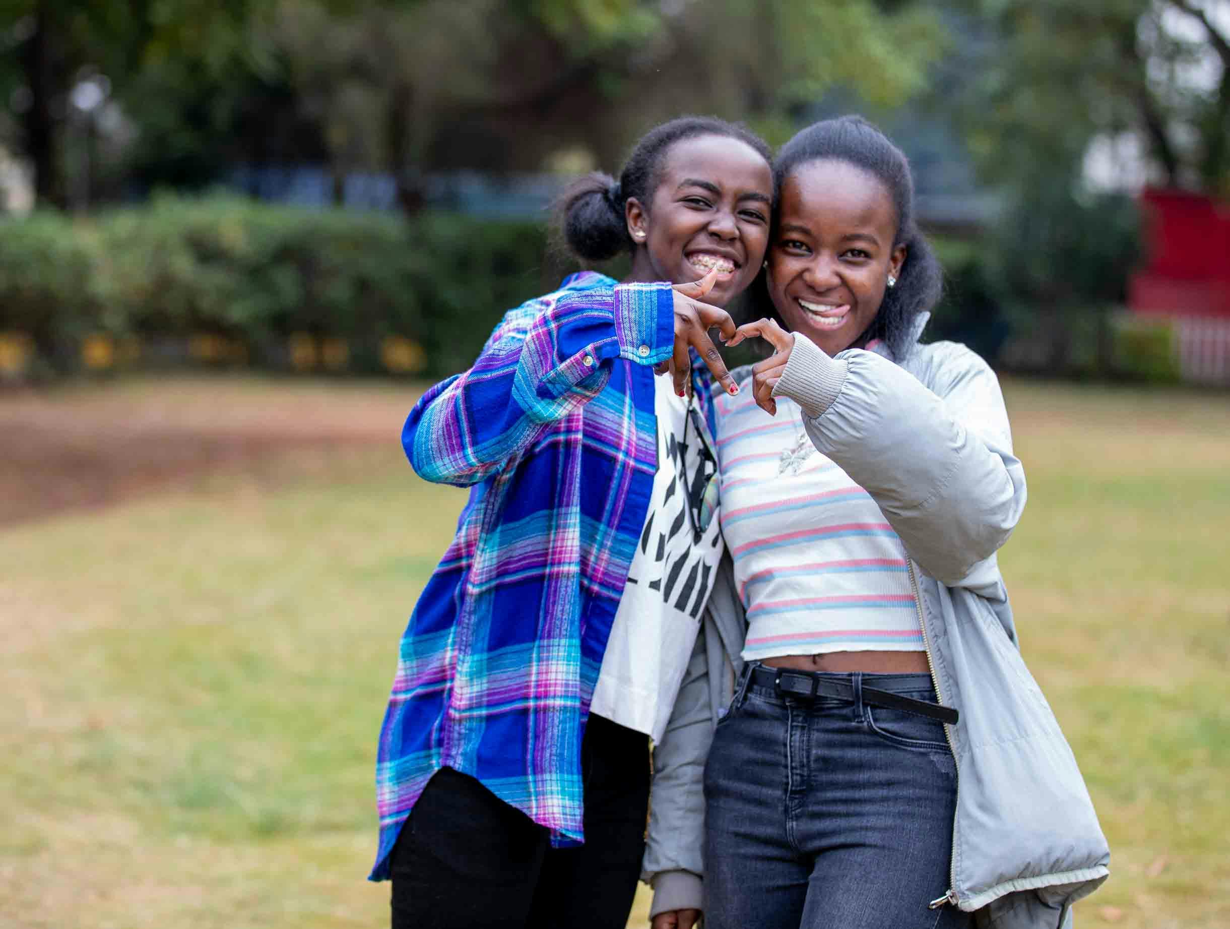 Two Black teens making a heart with their hands