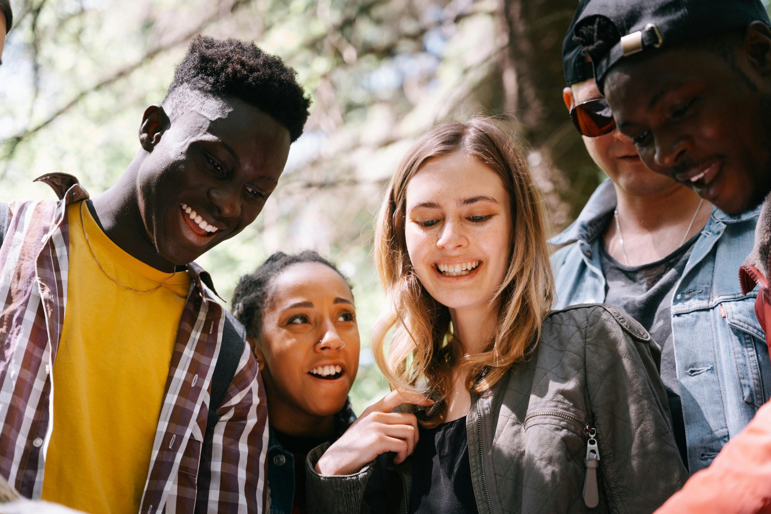 Four diverse teens looking at something together and smiling